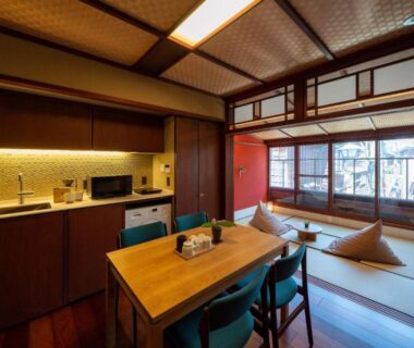 Tatami room with dining table, shoji screens and kitchenette at UTAIMACHI in Ishikawa, Chūbu