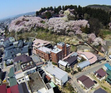 Aerial townscape with cherry blossom hillside near Uesugi no Miyu Gotenmori in Yamagata Tōhoku