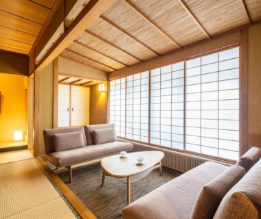 Bright tatami sitting room with low table, sofas, shoji screens and tokonoma at Uesugi no Miyu Gotenmori, Yamagata