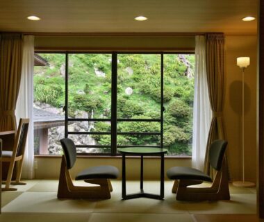 Tatami room with low table and zaisu chairs overlooking lush garden at Uesugi no Miyu Gotenmori, Yamagata