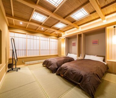 Tatami room with two low beds, shoji screens and wooden beam ceiling at Uesugi no Miyu Gotenmori, Yamagata