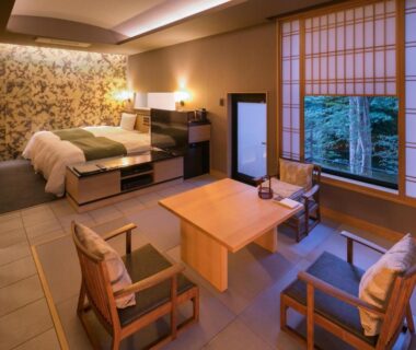 Room with twin beds, tatami seating area, low table and shoji window overlooking garden greenery