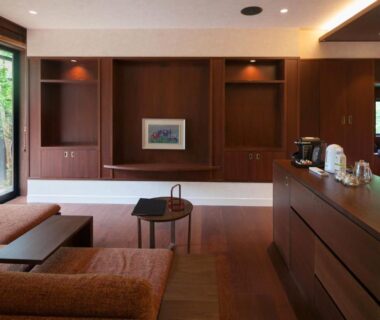 Spacious wood-paneled lounge with low table, sofa and garden view at Ufufu ryokan in Shizuoka