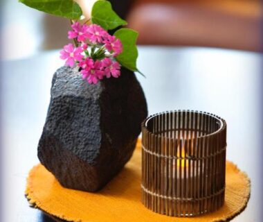 Rock vase with pink blossoms beside a lit candle on a low table at Ukiha ryokan, Ōita, Kyūshū, Japan