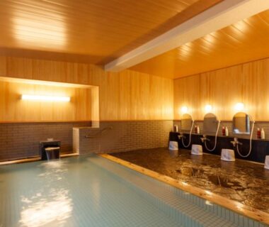 Indoor onsen bathing area with wooden walls and washing stations at Umemura Ryokan Uguisutei, Nagano, Chūbu, Japan