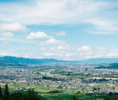 Wide elevated view over Nagano valley with town, rice fields and distant mountains