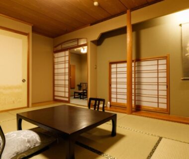 Traditional tatami room with low table, shoji screens and zabuton cushions at Umemura Ryokan Uguisutei, Nagano