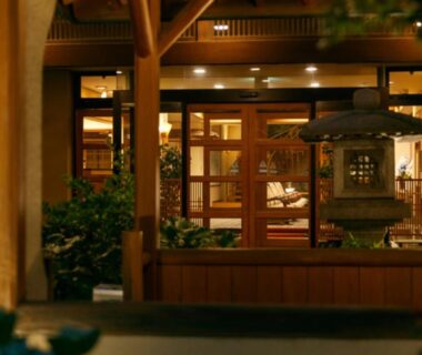 Warmly lit wooden entrance with shoji doors and stone lantern at Umemura Ryokan Uguisutei in Nagano