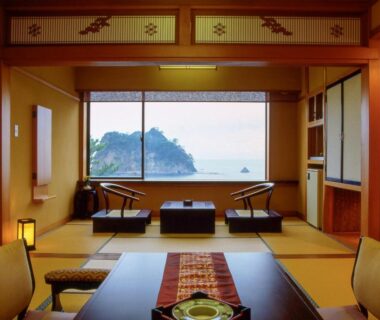 Traditional tatami room with low table and seating, large window framing sea and small island off Shizuoka coast