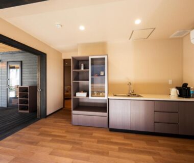Kitchenette with sink, cabinets and sliding partition to adjacent living area, hardwood flooring at Umine Annex Ōita
