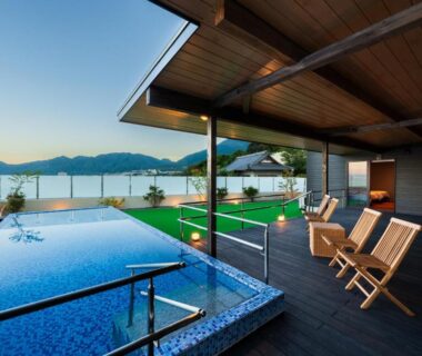 Covered rooftop onsen pools with wooden chairs overlooking a coastal bay at Umine Annex, Oita, Kyushu