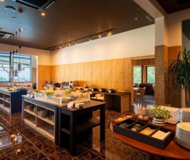 Buffet dining area with serving counters, plates and windows overlooking greenery at Umine Annex, Oita