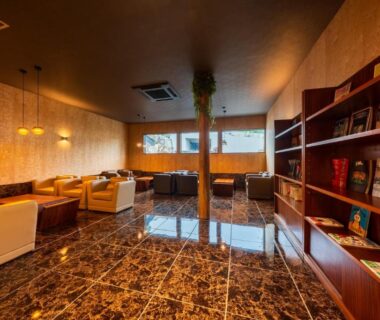 Polished marble lounge with sofas and bookshelves at Umine Annex, Ōita, Kyūshū