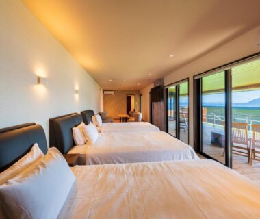 Three beds facing sliding glass doors and balcony with sea view at Umine Annex, Ōita, Kyūshū
