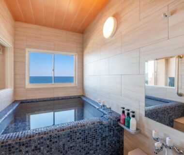 Tiled soaking bath with sea-view windows at Umino Hotel Hajime in Ōita, Kyūshū