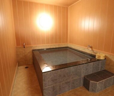 Indoor tiled bathing area with steps and wooden buckets at Umino Hotel Hajime, Oita, Kyushu, Japan