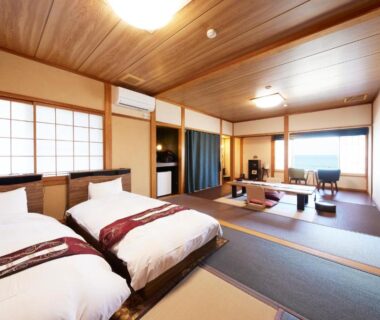 Spacious tatami room with twin Western beds, shoji screens, low table seating and large windows at Uminone in Hyōgo