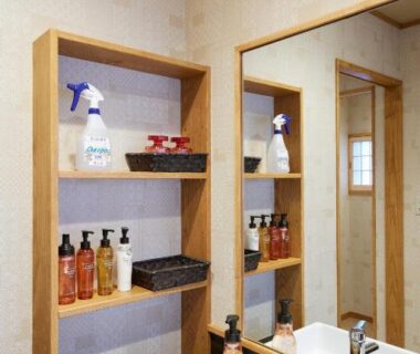 Wooden shelving with toiletries beside mirror and sink in a ryokan bathroom at Uminone, Hyōgo