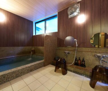 Stone soaking tub, shower stools and wood-paneled bath area at Uminone, Hyōgo, Kansai