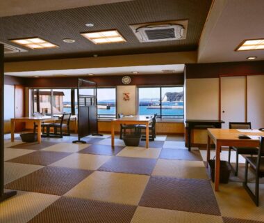 Spacious tatami dining with low tables, chairs, shoji screens and windows overlooking a waterfront in Chiba