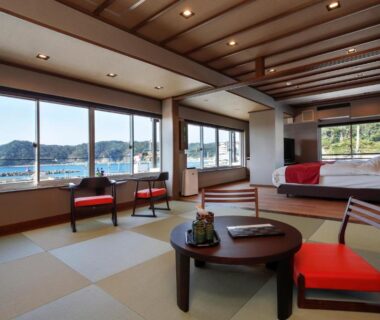 Tatami room with low table, red chairs and windows overlooking coastal bay at Uminoniwa, Chiba