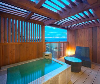 Wooden terrace with tiled soaking tub, lounge chair and lantern, open view toward the sea at Umiusagi Shizuoka