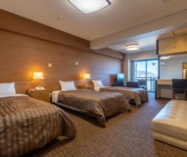 Spacious western-style room with three single beds, sofa and balcony at Uomisaki Hotel in Chūbu, Shizuoka, Japan