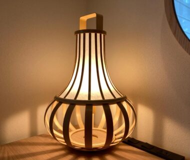 Warm wooden lantern with slatted frame on a tabletop near a round shoji window in a ryokan room