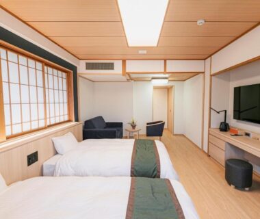 Bright twin beds room with shoji screen, wooden ceiling, seating area and wall-mounted television at Ureshino Motoyu Saga