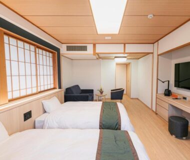 Twin beds with shoji screens, wooden ceiling, seating area and TV at Ureshino Motoyu in Saga, Kyushu, Japan