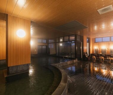 Wood-paneled indoor onsen with stone bathing pool and stools at Ureshino Motoyu in Saga, Kyūshū, Japan