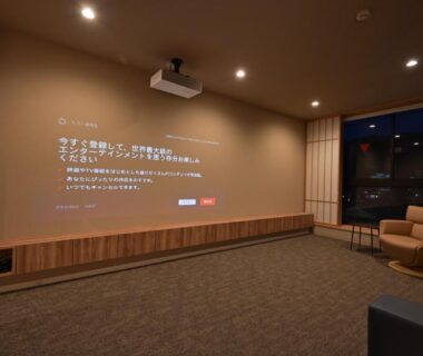 Indoor projection lounge with wall screen, ceiling projector, chairs and bench at Ureshino Onsen ryokan in Saga