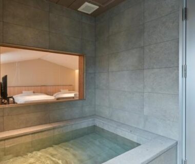 Stone onsen bath with interior window overlooking a sleeping area at Ureshino Onsen Yusyuku Sarayama, Kyushu