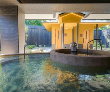Indoor onsen with circular stone tub and wooden shelter at UreshinoOnsen URESHINO YADOYA, Saga