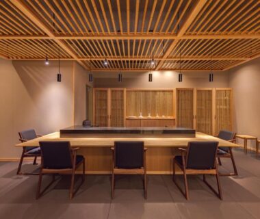 Long wooden counter seating with low-backed chairs under slatted ceiling in UreshinoOnsen URESHINO YADOYA Saga