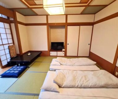 Traditional tatami room with futon bedding, shoji screens, low table and cushions at Uruoikan, Nagano