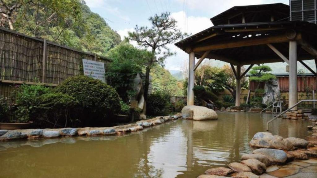 Outdoor onsen at Uruoikan Nagano Covered outdoor onsen bath with stone edging and garden at Uruoikan in Nagano