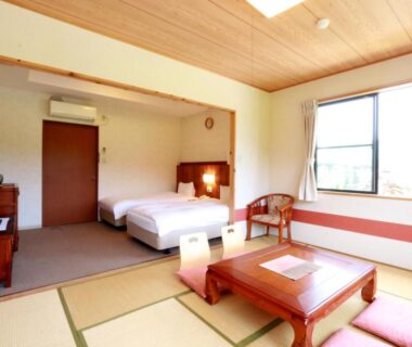 Tatami room with low table, cushions and two beds at Usuki Yunosato in Ōita, Kyūshū