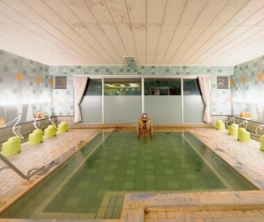 Communal indoor onsen with tiled pool and side washing stations at Villa Inawashiro, Fukushima Tōhoku