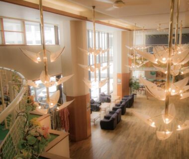 Spacious ryokan lobby with suspended leaf chandeliers, wooden flooring, seating and tall windows at Villa Inawashiro, Fukushima