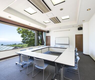 U-shaped meeting room with large window and coastal view at Village Izukogen in Shizuoka