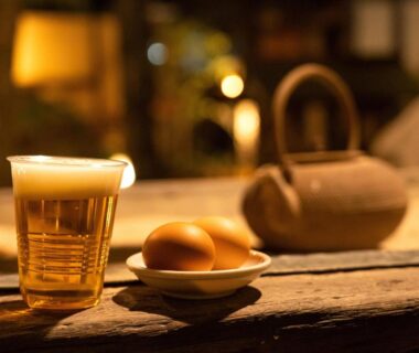 Frothy beer, eggs and ceramic teapot on wooden counter at Wa no Yado Sagiritei, Ōita, Kyūshū, Japan