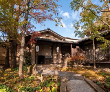 Stone path leading to wooden ryokan entrance with autumn foliage at Wa no Yado Sagiritei in Ōita, Kyūshū