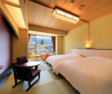 Tatami room with twin beds, seating area and mountain view at Wafu-no-Yado MASUYA in Nagano