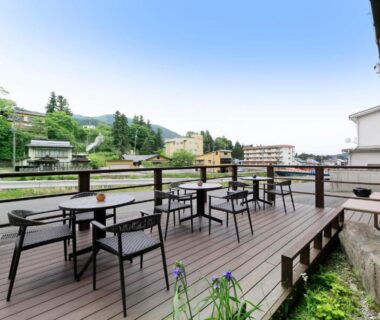 Outdoor riverside wooden deck with tables and chairs at Wafu-no-Yado MASUYA in Nagano