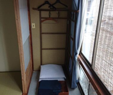 Folded futon and pillow beside bamboo blinds in tatami room at Wajimaya Ryokan Kyoto Kansai