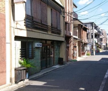 Narrow street with Wajimaya Ryokan entrance, wooden facade and overhead utility wires in Kyoto