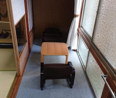 Narrow engawa corridor with low wooden table and chairs beside a tatami room at Wajimaya Ryokan Kyoto