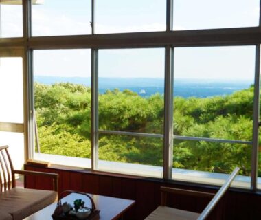 Large glass windows overlooking green hills and blue horizon, wooden lounge at Wakaki Ryokan, Nasu Yumoto, Tochigi