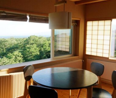 Round dining table and chairs by large window overlooking forest at Wakaki Ryokan Nasu Yumoto Onsen Tochigi